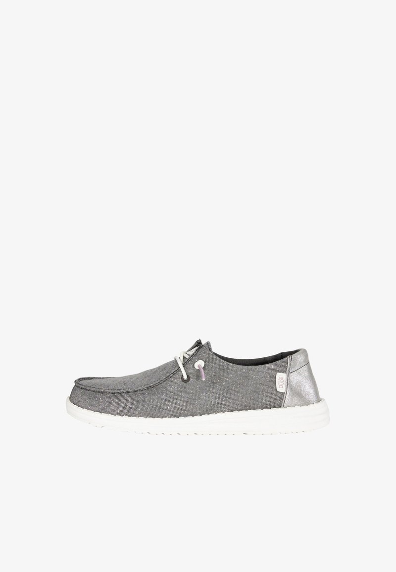 Zapato casual slip-on de tela gris para hombre con cordones blancos, suela blanca y detalle metálico plateado en el talón, etiqueta de la marca en el lateral.