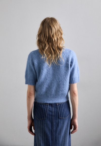 Sinine lühikeste varrukatega sviiter pehmest ja tekstuursetest kangast, millele on sobitatud denimhame, millel on vertikaalsed triibud ja tagataskud.