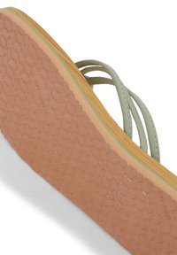 Gröna sandaler med remmar och en texturerad gummisula, som har en brun och beige botten samt tunna remmar. Ergonomisk design för komfort.