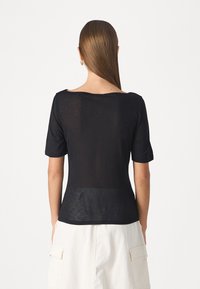 Black short-sleeve top with a loose fit, featuring a wide neckline and sheer texture, showcasing a simple, minimalist design.