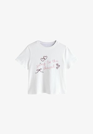 Valkoinen t-paita, jossa on lyhyet hihat, vaaleanpunainen kirjailtu teksti "going to the chapel" sekä mustalla ääriviivalla piirretyt sydämet ja rusetti edessä.