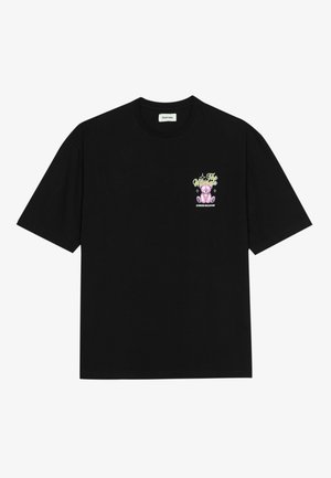 T-shirt noir à manches courtes avec un petit graphisme d'ours en peluche violet et le texte « Le meilleur antidépresseur » sur la poitrine gauche.