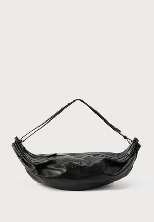 Sac à bandoulière en cuir noir avec sangle réglable, compartiment principal zippé et forme légèrement souple sur un fond clair uni.