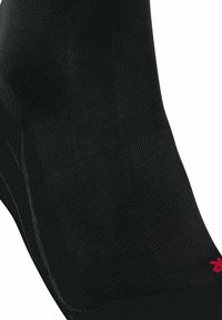 Calzino sportivo nero con una texture a coste, punta e tallone rinforzati, e un piccolo logo rosso sul lato esterno.