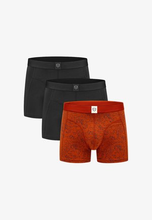 Kolm meestele mõeldud bokserit, kaks ühtlase musta värviga ja üks põletatud oranž musta abstraktse mustriga, igaühel logo vöö keskosas.