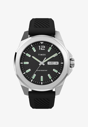 Timex pulksteņi ar melnu ciparnīcu, sudraba tonī korpusu un zaļiem stundu rādītājiem. Iekļauj gumijas jostu un rāda datumu un ūdensizturību.