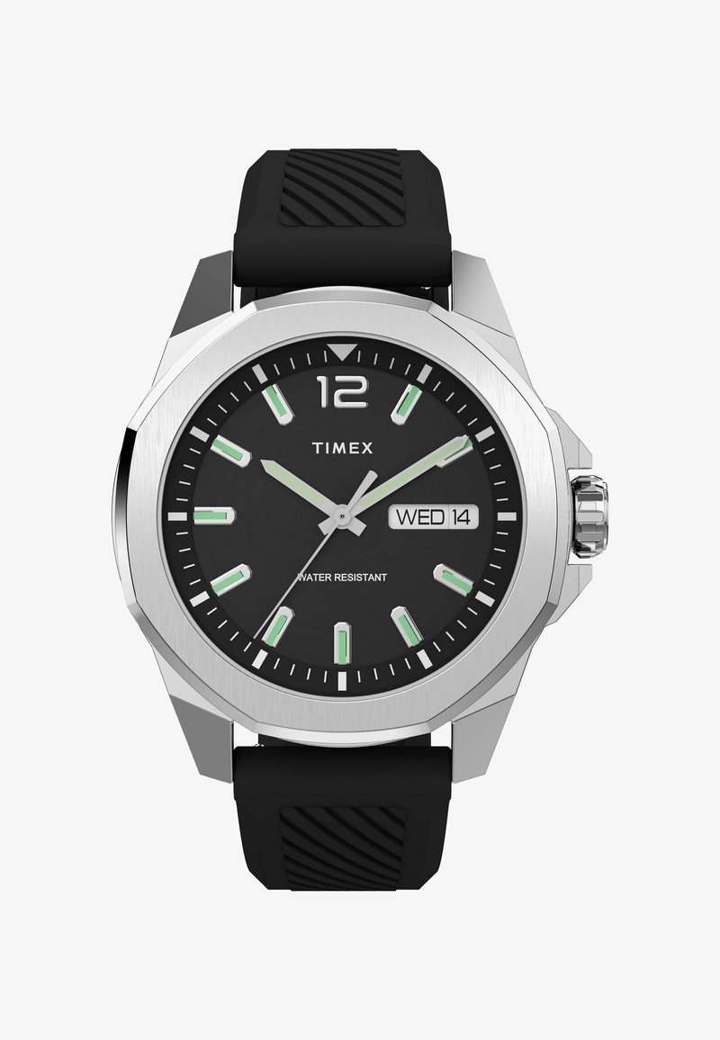 Timexi kell musta küllaga, hõbedase korpuse ja roheliste tunni markeritega. Omab kummist rihma ning näitab kuupäeva ja vettpüsivust.