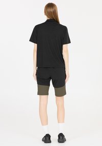 Svart kortärmad skjorta, kombinerad med svart och grön färgblockerad shorts. Outfiten är designad för komfort och har en avslappnad passform.