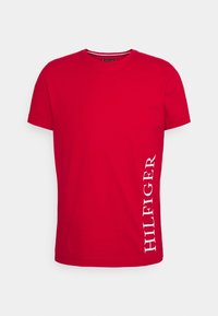 Červené bavlněné tričko s kulatým výstřihem, na levé straně s bílým textem "HILFIGER". Krátké rukávy a klasický střih.