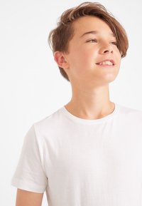 Maglietta bianca in cotone con maniche corte e scollatura a girocollo. Presenta una texture morbida e un design semplice, adatta per l'abbigliamento casual.