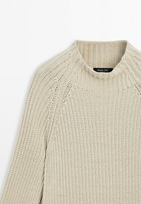 Beige strikket sweater med ribstrikket rund halsudskæring og raglanærmer, der viser detaljeret strikket struktur og Massimo Dutti-mærke inde i kraven.