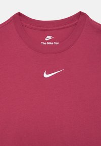 T-shirt Nike bordeaux avec un col rond, fabriqué en coton doux ; présente un logo Nike blanc sur la poitrine. Texture lisse et coupe classique.