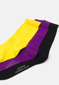 Three pairs of ankle socks in yellow, purple, and black. Made from ribbed fabric with elasticized cuffs, sizes 39-42 are printed on each.
