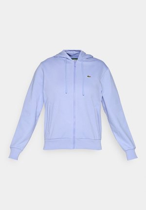 Lys lilla zip-up hettegenser med frontlommer, snorhette, ribbede mansjetter og en liten grønn krokodille-logo på venstre bryst.