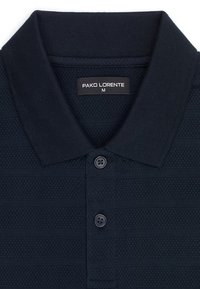 Granatowa, fakturowana koszulka polo z kołnierzykiem, dwoma guzikami oraz metką "PAKO LORENTE" rozmiar M wewnątrz kołnierza.