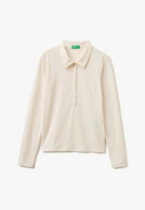Polo a manica lunga color crema con sei bottoni e colletto a punta, con etichetta verde "United Colors of Benetton" all'interno del collo.