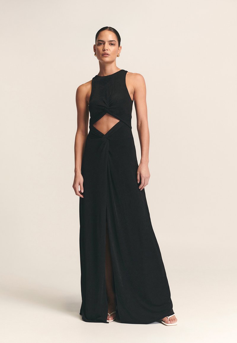 Musta maksimekko, valmistettu pehmeästä kankaasta, jossa on halter-kaulus, kiertodetalji, vyötäröllä leikattu alue ja eteen sijoitettu halkio visuaalisen kiinnostavuuden lisäämiseksi.