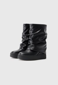 Bottines noires en cuir lisse avec un design décontracté, semelle épaisse et détails texturés.