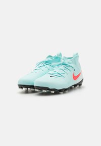 Turkoosi jalkapallokengät, joissa on vaaleanpunainen swoosh, sileä synteettinen yläosa, musta ulkopohja valkoisilla napeilla ja standartti nauhoitusjärjestelmä.