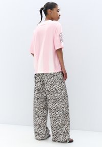Růžové pruhované oversized tričko s krátkými rukávy, sladěné s volnými, lehkými béžovými kalhotami s leopardím potiskem.