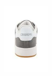 Baskets grises avec un empiècement de talon blanc et une semelle en gomme. Présente une finition texturée et un logo "Kappa" bien visible à l'arrière en argent.
