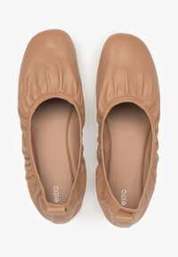 Jasnobrązowe baleriny ze skórzanej cholewki, z marszczonym wykończeniem wokół krawędzi, okrągłym noskiem i wyściełanym wnętrzem dla większego komfortu. Widać logo marki.