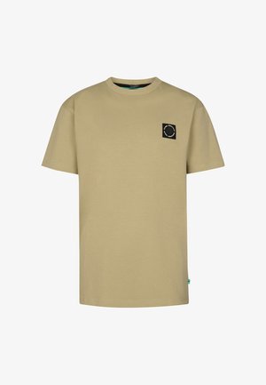 Tanfarvet bomulds-t-shirt med rund hals og sort logo-patch, kombineret med blå slim-fit jeans og hvide sneakers. Simpelt design og afslappet pasform.