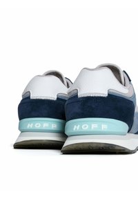 Niebiesko-białe sneakersy charakteryzują się połączeniem materiałów skórzanych i zamszowych, mają zaokrąglony kształt oraz jasnoniebieską podeszwę z logo "HOFF".