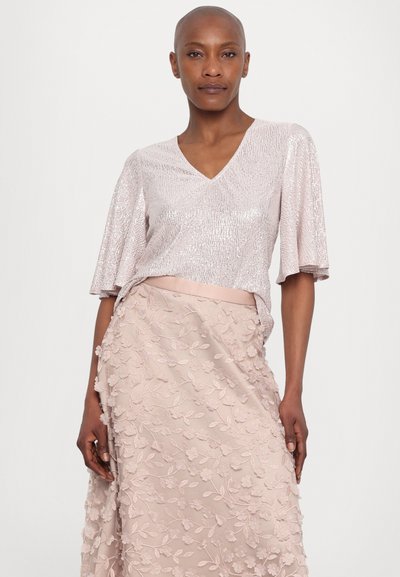 Pale pink top with V-neck and short sleeves featuring a textured, shiny finish. Flowing skirt with floral embroidery in matching pink tones.