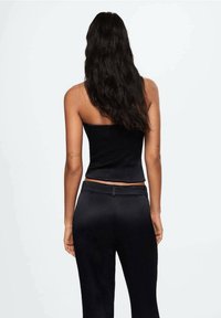 Top nero corto senza spalline con un design aderente, abbinato a pantaloni neri a vita alta coordinati. Tessuto liscio e lucido con una morbida texture.