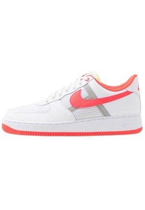 Baskets basses blanches avec le logo Nike en forme de virgule rose, doublure intérieure rose, et accents roses sur la semelle, composées de matériaux en mesh et cuir.