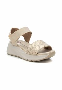 Sandalias de cuña beige con parte superior perforada, correa ajustable en el tobillo, plantilla acolchada y suela texturizada para un mejor agarre.