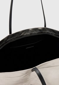Borsa a tracolla con un design strutturato, caratterizzata da un esterno nero e un interno di colore chiaro a contrasto. Texture liscia con chiusura a zip.