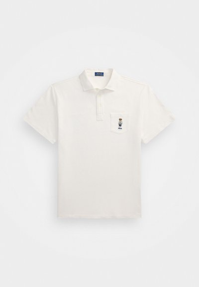 Biele polo tričko vyrobené z bavlny s klasickým golierom, krátkymi rukávmi a vreckom s vyšitým logom.