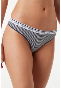 String rayé avec une taille élastique douce, comportant un logo "next" répété. Le schéma de couleurs comprend des rayures bleu marine et blanches.