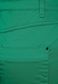 Grön tyg med en slät yta, med en bakficka med en metallnitts, avslutad med snygg sömnad och en rak kantdesign.