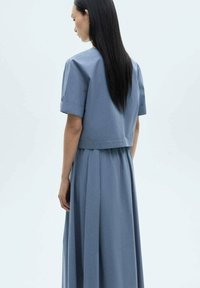 Blue dress made of lightweight fabric, featuring a cropped top with short sleeves and a flowing A-line skirt, viewed from the back.
