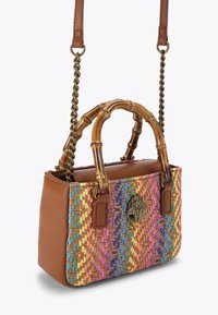 Mała prostokątna torebka z wielokolorowym splotem, brązowymi skórzanymi bokami, bambusowymi uchwytami oraz złotym zapięciem w kształcie ręki z czarnym kamieniem.