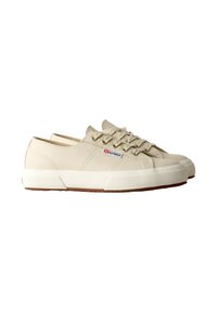 Zapatillas de lona beige con punta redonda, cordones beiges y suela de goma blanca. Textura en relieve notable en la suela y un pequeño logo cerca del talón.
