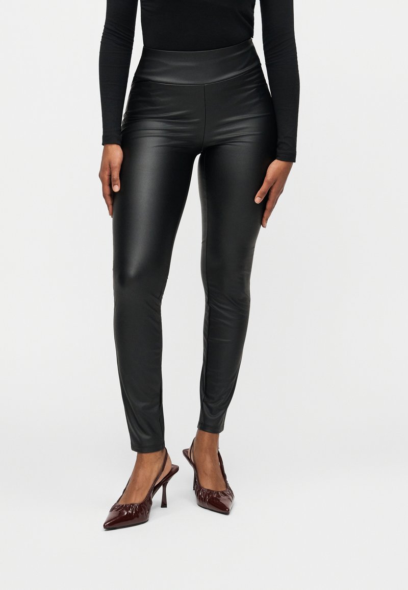 Μαύροι κολάν από τεχνητό δέρμα με ψηλή μέση, λεία υφή, εφαρμοστή γραμμή και μήκος μέχρι τον αστράγαλο, σε συνδυασμό με μπορντό μυτερά τακούνια.