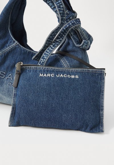 Borsa tote in denim con manico arricciato e pochette con zip staccabile. La borsa e la pochette presentano una texture in denim blu con un marchio bianco.