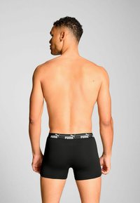 Black boxer briefs made of cotton, featuring a soft waistband with white "Puma" branding, viewed from the back.