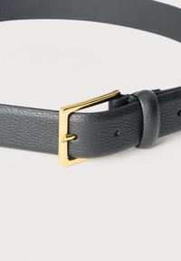 Cinturón de cuero negro texturizado con una hebilla rectangular dorada y una presilla de cuero sobre un fondo blanco.