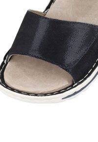 Námořnické modré skluzné sandály s texturovaným textilem na svršku, otevřenou špičkou a měkkou béžovou stélkou. Jsou zdobeny bílým prošitím a mají polstrovanou podrážku.