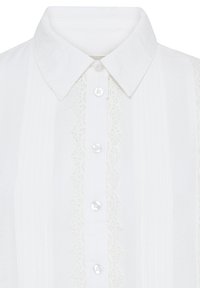Chemise blanche boutonnée avec col pointu, détails en dentelle verticale et quatre boutons ronds blancs visibles sur la patte de boutonnage avant.