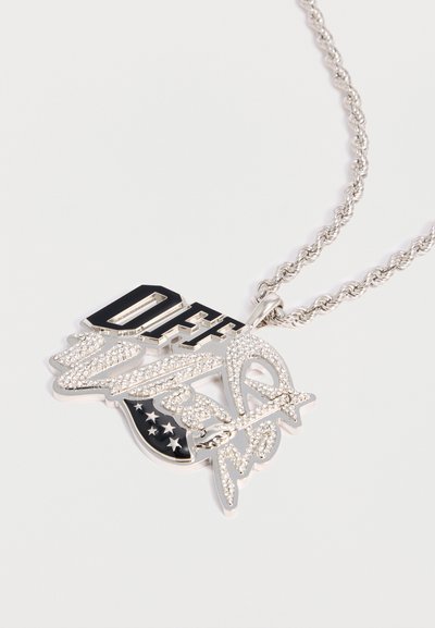 Ασημένιο κολιέ με αλυσίδα και μενταγιόν που απεικονίζει το «OFF» σε μαύρο και το «Wear» σε στρας, μαζί με ένα στοιχείο σχεδίου με σημαία διακοσμημένη με αστέρια.