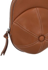 Kerek barna bőrtáska kontrasztos fehér varrással, központi gombdísszel és cipzáras záródással. Texturált felület enyhe fényű.