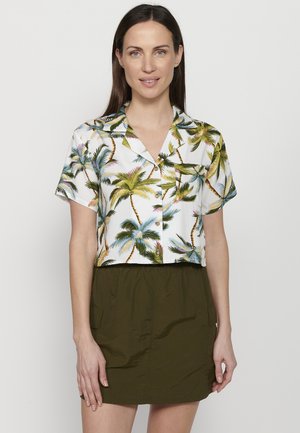Cropped white shirt with green and yellow palm tree pattern, short sleeves, and a button-up front, paired with an olive green skirt.