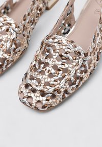 Zapatos tejidos en tonos metálicos de oro, plata y bronce. Diseño de punta abierta, con un patrón tejido texturizado y transpirable.