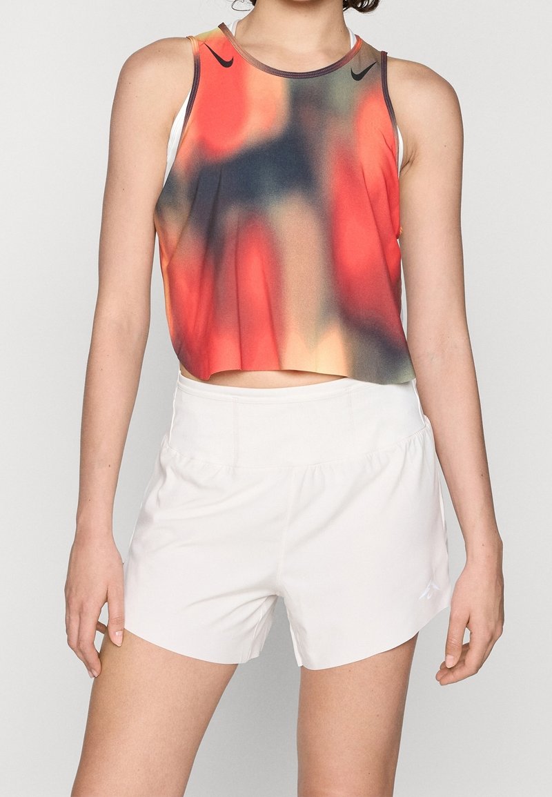 Czerwony, pomarańczowy i niebieski crop top w gradientowym wzorze z okrągłym dekoltem; zestawiony z białymi szortami z elastycznym pasem i minimalistycznym designem.